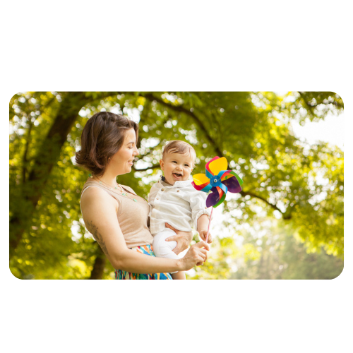Mãe segura filho e cata vento no colo em um ambiente de floresta