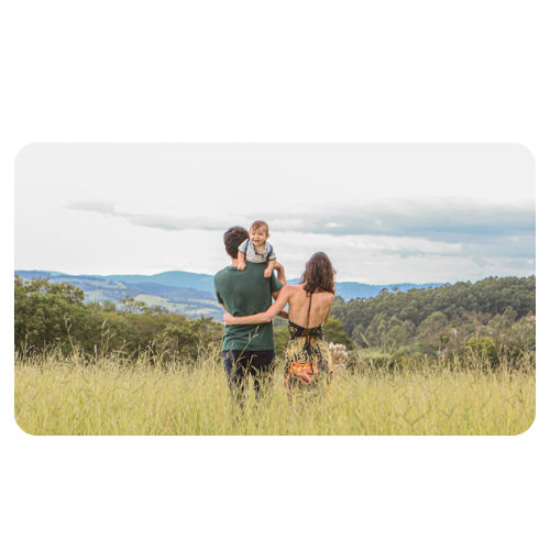 Casal andando de costas com bebê apoiado no ombro do pai