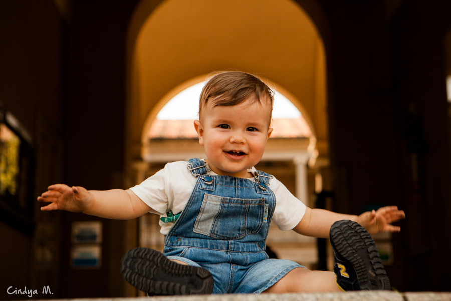 Bebê sentado de braços abertos sorrindo
