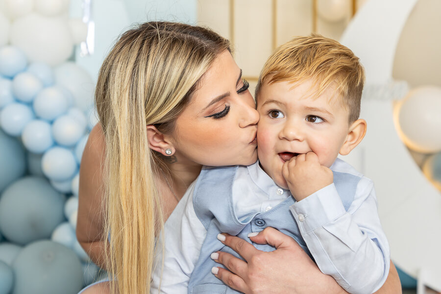 Mãe a dar um beijo ao filho no dia do seu batizado