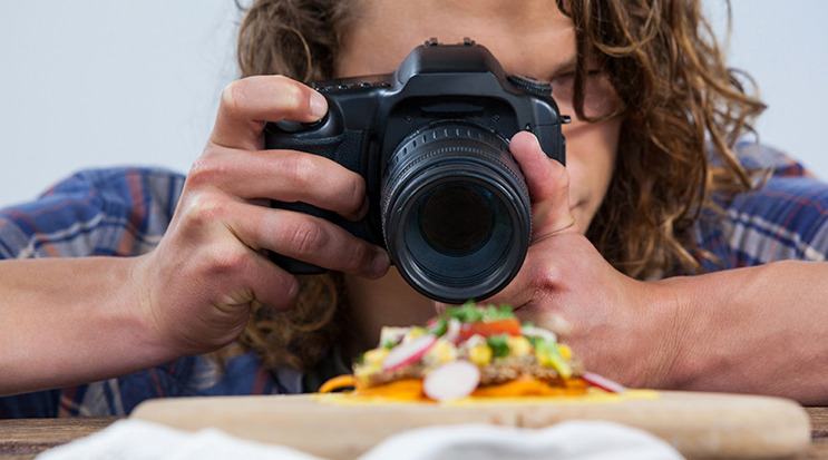 Fotógrafo clicando em uma foto de comida usando câmera digital