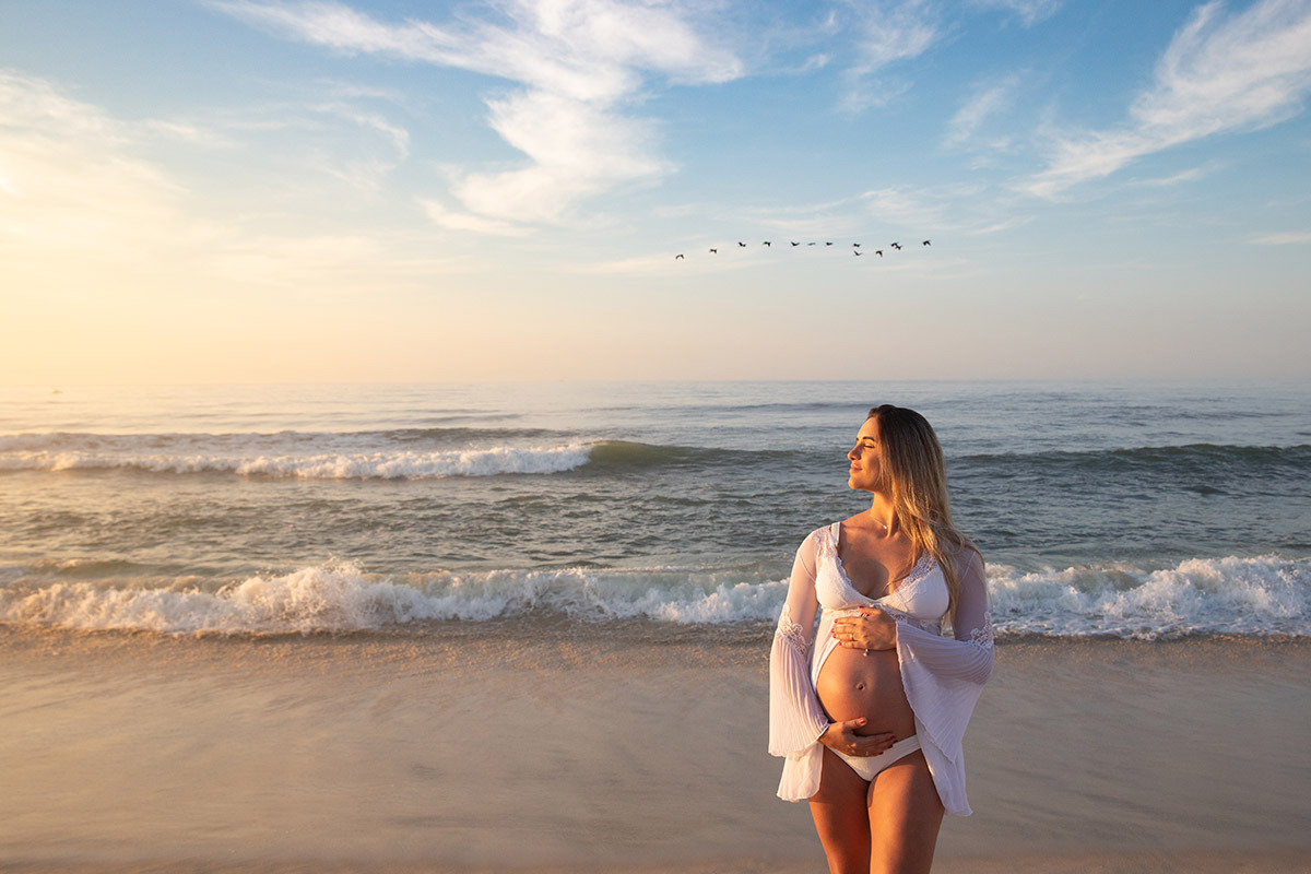 gestante na praia ao nascer do sol