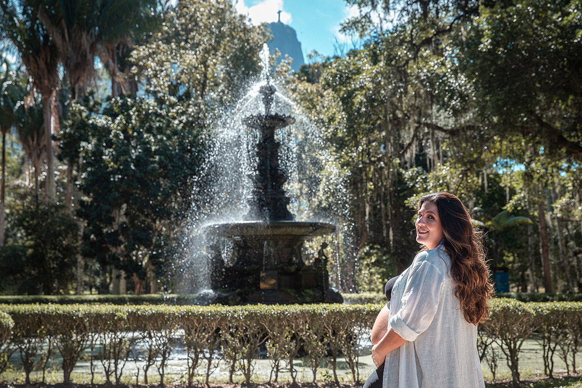 gestante sorrindo ao lado do chafariz do Jardim Botânico do Rio de Janeiro