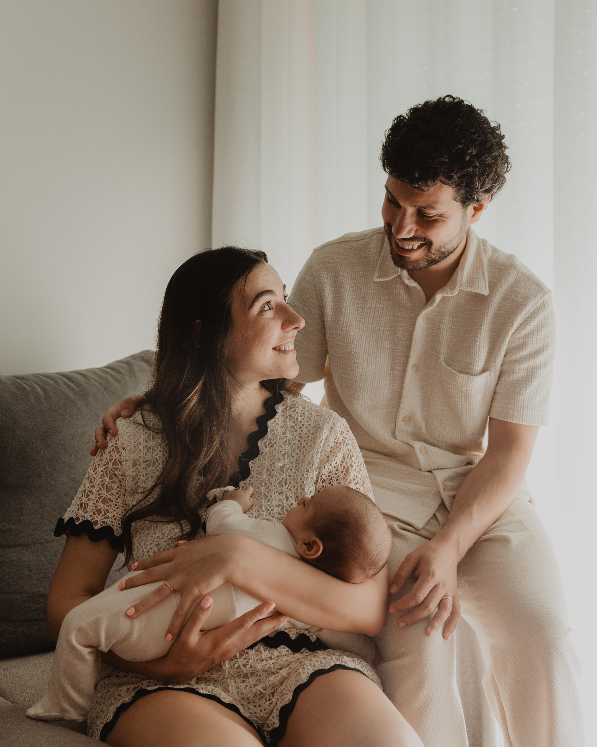 Sessão fotográfica íntima em casa, capturando os primeiros momentos em família com o recém-nascido.
