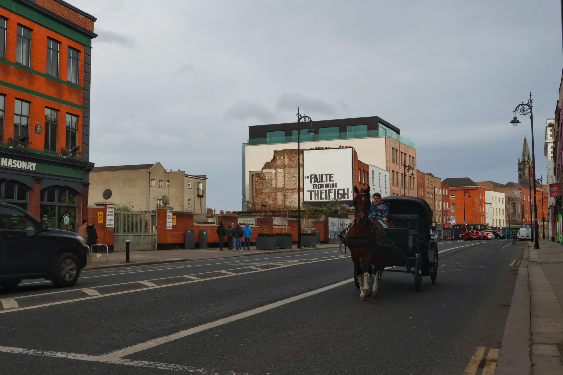 Cena de rua na Irlanda com uma charrete e cavalo em movimento, capturando a dinâmica do transporte tradicional em um ambiente urbano, feita por ex-aluno do curso, aplicando técnicas de velocidade do obturador para registrar o movimento ou congelar a cena.
