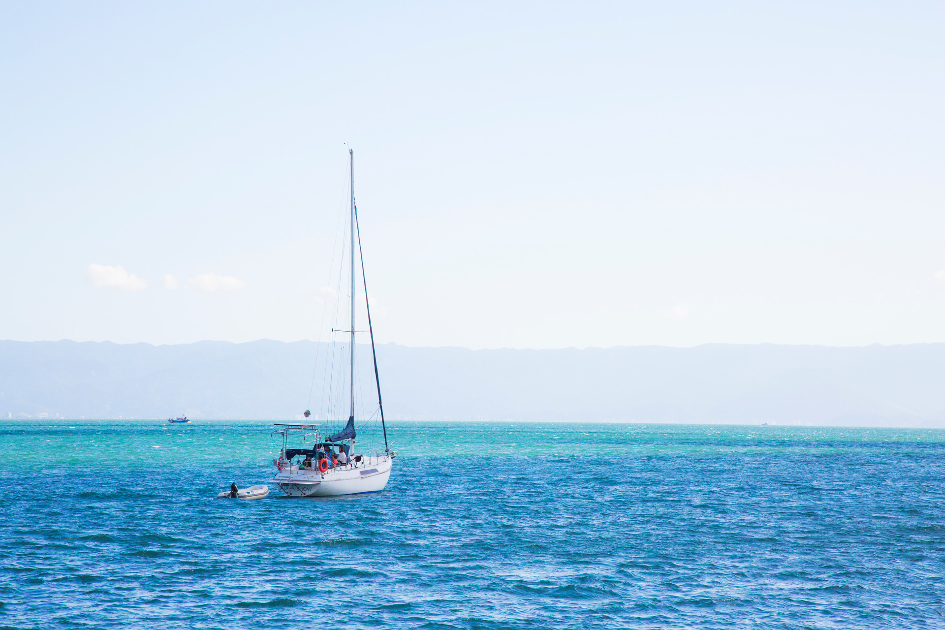 Fotografia de um barco navegando em águas azuis cristalinas no mar de Ilhabela, São Paulo, transmitindo serenidade e a beleza natural do litoral.
