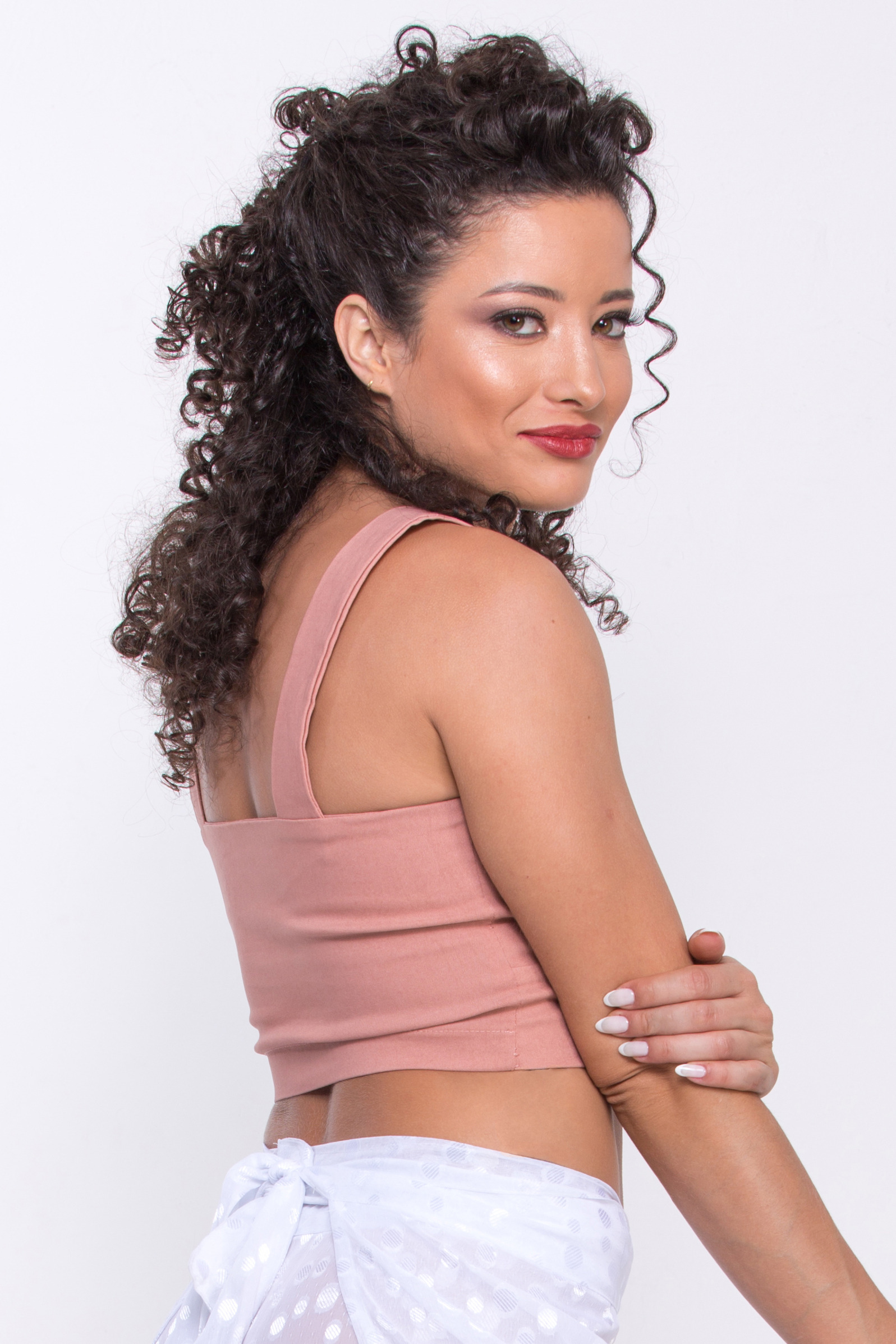 Fotografia editorial em plano médio de modelo feminina olhando elegantemente por cima dos ombros, vestindo roupa leve e fluida, com foco em sua expressão e na atmosfera de verão.