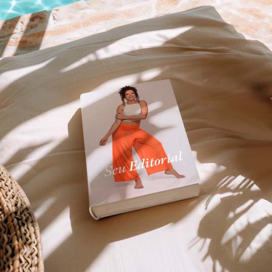 Álbum fotográfico fechado sobre uma espreguiçadeira perto da piscina, com a capa mostrando uma modelo feminina de corpo inteiro vestindo roupa leve de verão, sugerindo um editorial de moda ou estilo de vida.