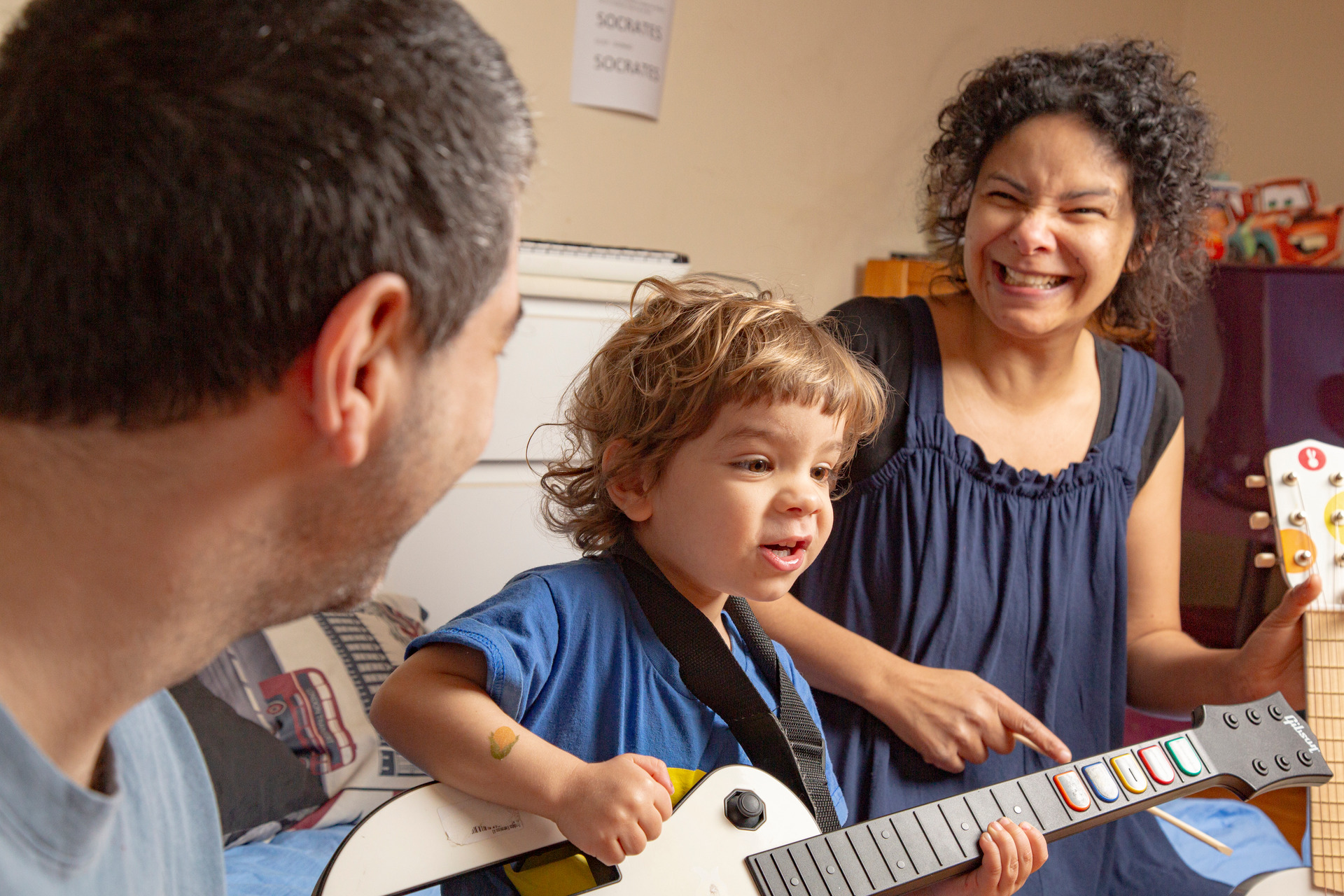 Retrato de família criança ao centro tocando guitarra de brinquedo em foto espontanea em ensaio de família por Bruno Arita