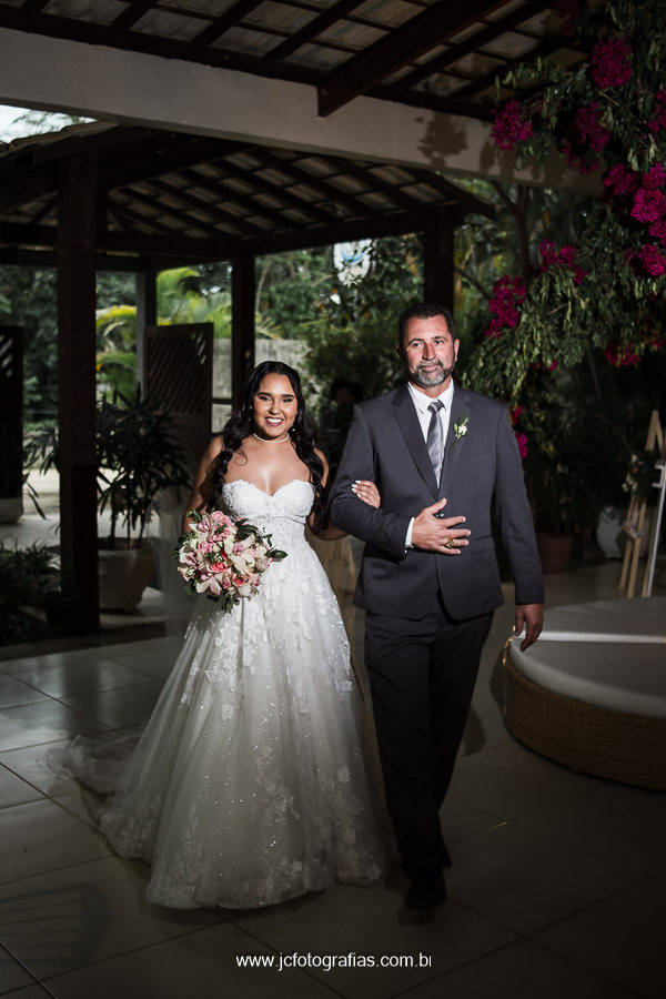 noiva entrando na cerimonia sorrindo acompanhada de seu pai