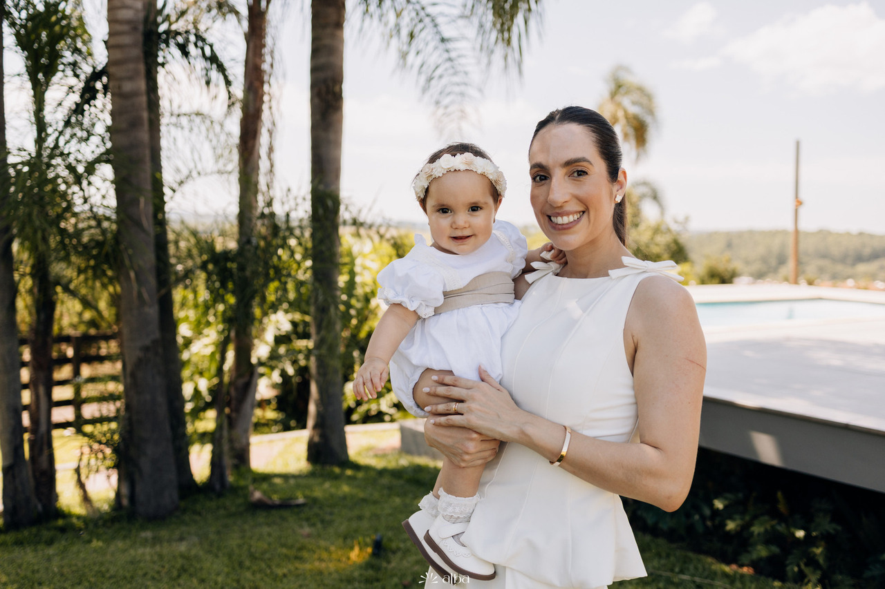 Mãe e filha em retrato ao ar livre após o batizado da Amália, registrando a alegria e a serenidade deste dia inesquecível. Foto por Alba Estúdio.