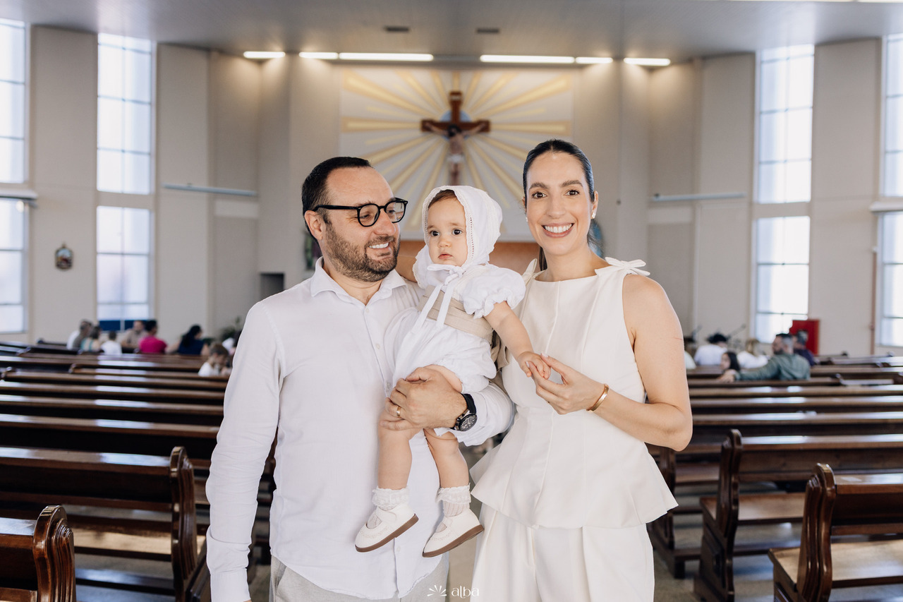 Retrato da família dentro da Paróquia São Cristóvão após a cerimônia de batismo, celebrando o início da jornada cristã da Amália. Foto por Alba Estúdio.
