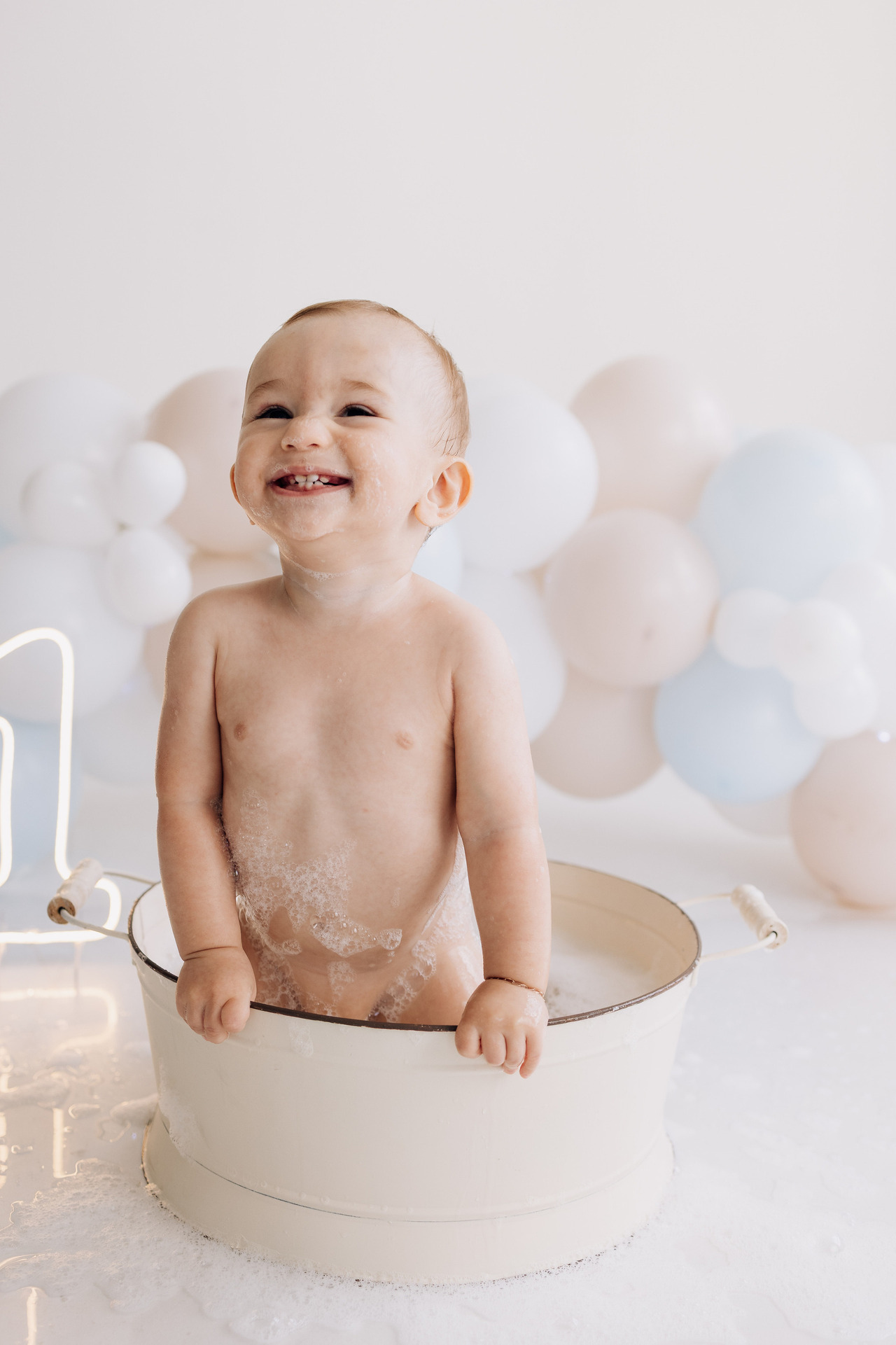 Bebê Luca sorrindo durante o banho de espuma após smash the cake no ensaio de acompanhamento mensal no Alba Estúdio em Lajeado.
