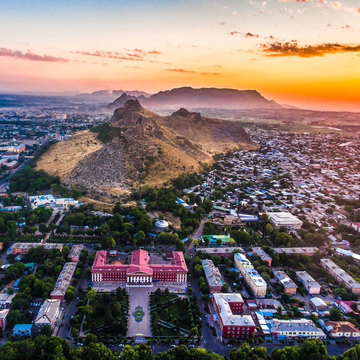 Aerial view of Osh city at sunset with mountains and green streets